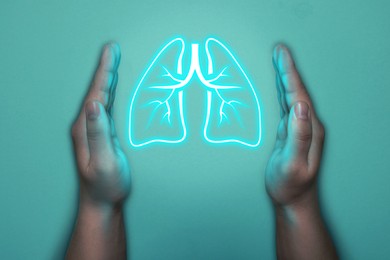 Image of Woman holding hands near neon lungs on turquoise background, closeup. Asthma and other respiratory diseases