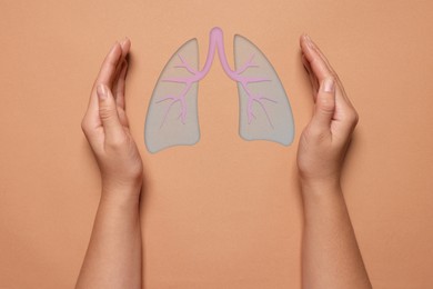 Image of Woman holding hands near illustration of lungs on color background, closeup. Asthma and other respiratory diseases