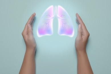 Image of Woman holding hands near illustration of lungs on light blue background, closeup. Asthma and other respiratory diseases