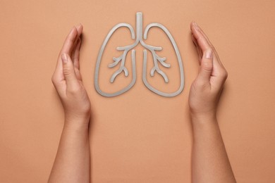 Image of Woman holding hands near illustration of lungs on color background, closeup. Asthma and other respiratory diseases