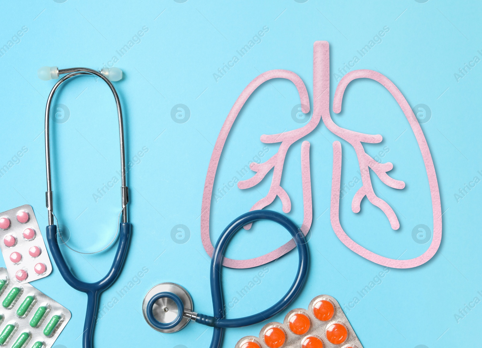 Image of Stethoscope, drugs and illustration of lungs on light blue background, flat lay. Asthma and other respiratory diseases