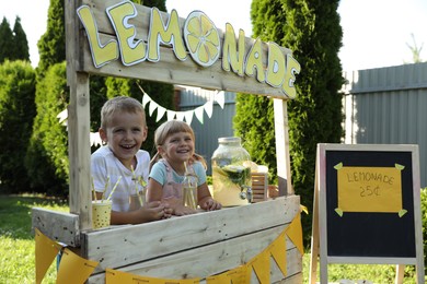 Cute little kids with refreshing drinks at lemonade stand in park