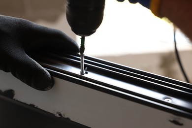 Photo of Repairman installing new window with electric screwdriver indoors, closeup