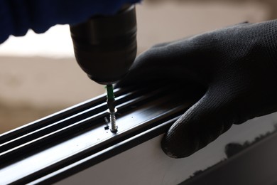 Photo of Repairman installing new window with electric screwdriver indoors, closeup