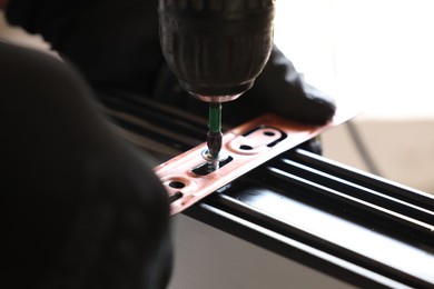 Photo of Repairman installing new window with electric screwdriver indoors, closeup