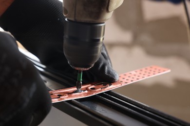 Photo of Repairman installing new window with electric screwdriver indoors, closeup