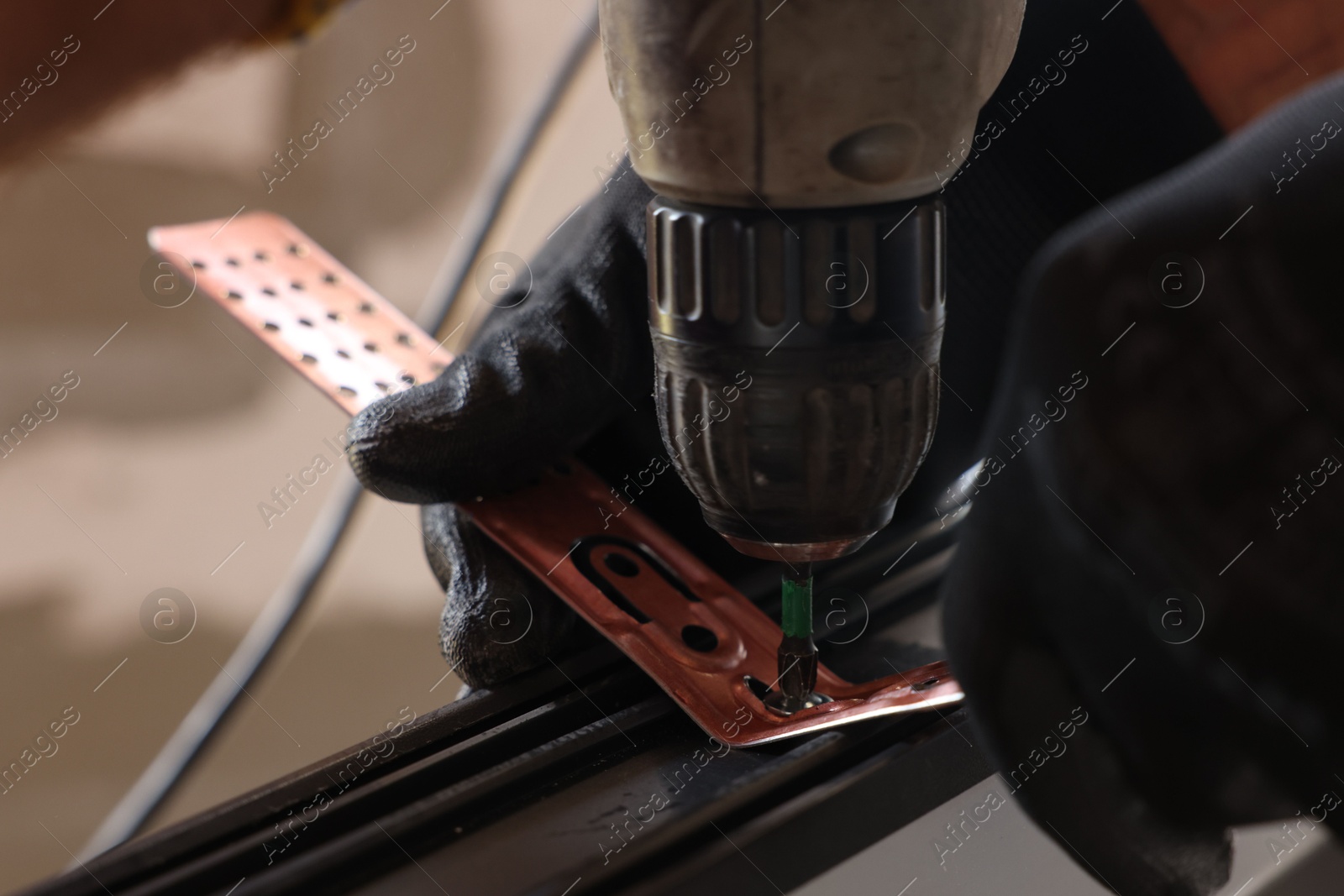 Photo of Repairman installing new window with electric screwdriver indoors, closeup