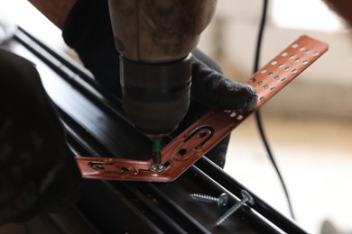 Photo of Repairman installing new window with electric screwdriver indoors, closeup