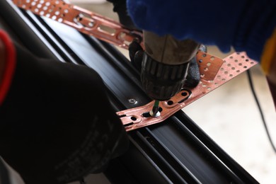 Photo of Repairman installing new window with electric screwdriver indoors, closeup