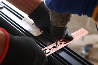 Photo of Repairman installing new window with electric screwdriver indoors, closeup