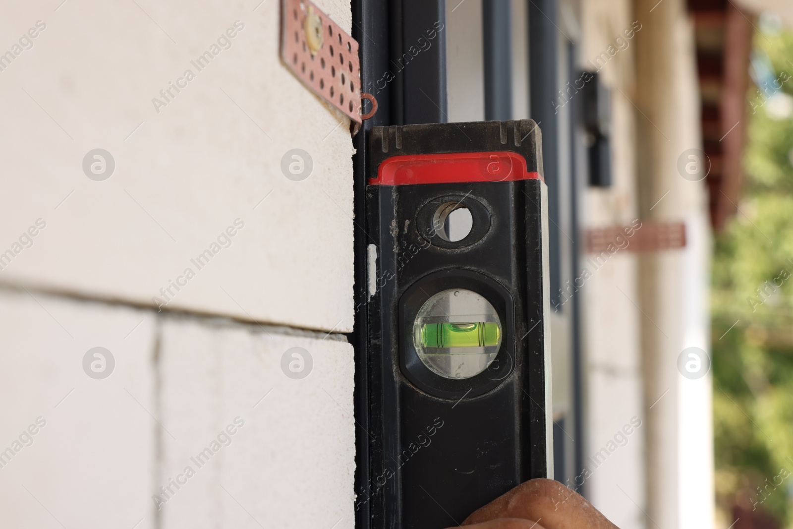 Photo of Repairman with building level installing new door at home, closeup