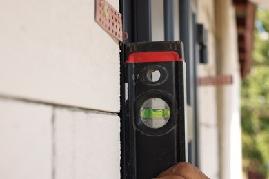 Photo of Repairman with building level installing new door at home, closeup