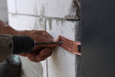 Photo of Repairman installing new door with electric screwdriver indoors, closeup