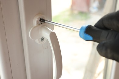 Photo of Repairman installing new window with screwdriver indoors, closeup