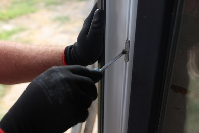 Photo of Repairman installing new window with screwdriver indoors, closeup