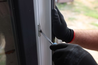 Photo of Repairman installing new window with screwdriver indoors, closeup