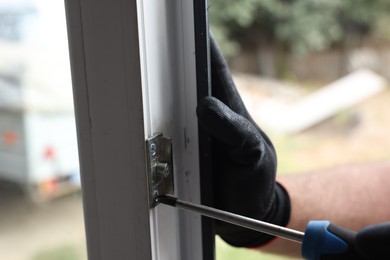 Photo of Repairman installing new window with screwdriver indoors, closeup