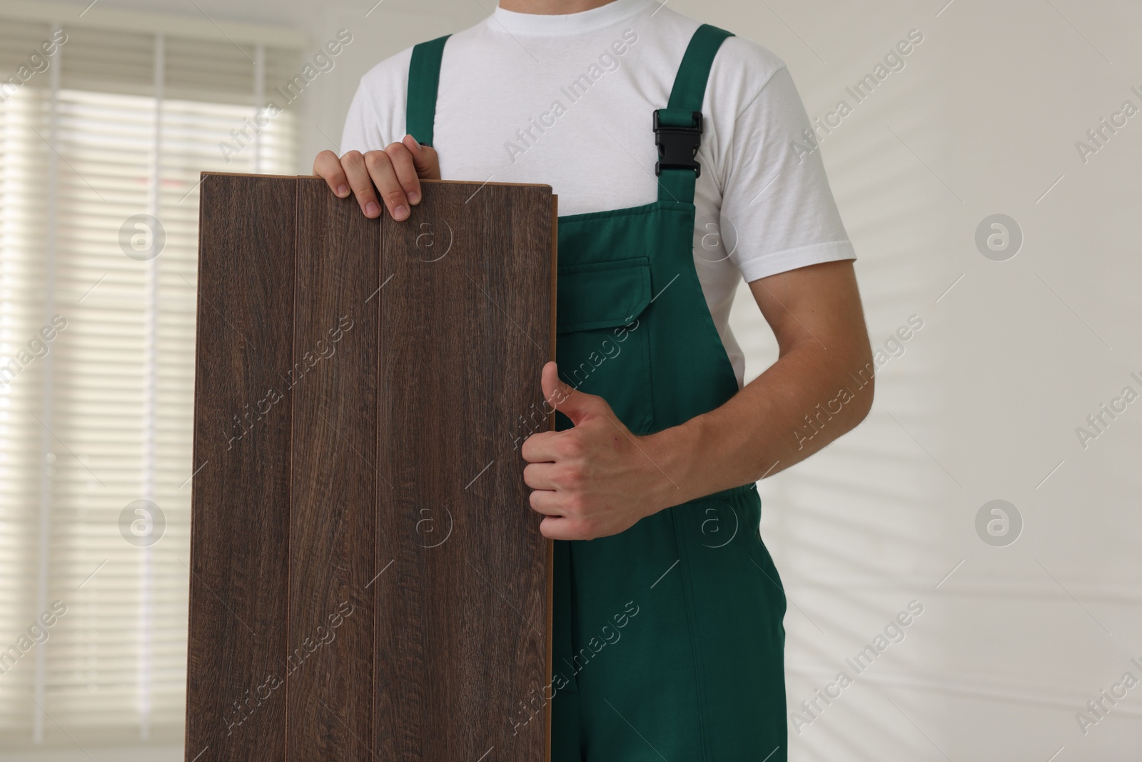 Photo of Worker with samples of wooden flooring showing thumbs up indoors, closeup