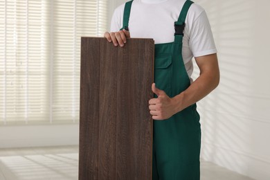 Photo of Worker with samples of wooden flooring showing thumbs up indoors, closeup