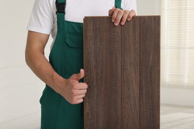 Photo of Worker with samples of wooden flooring showing thumbs up indoors, closeup