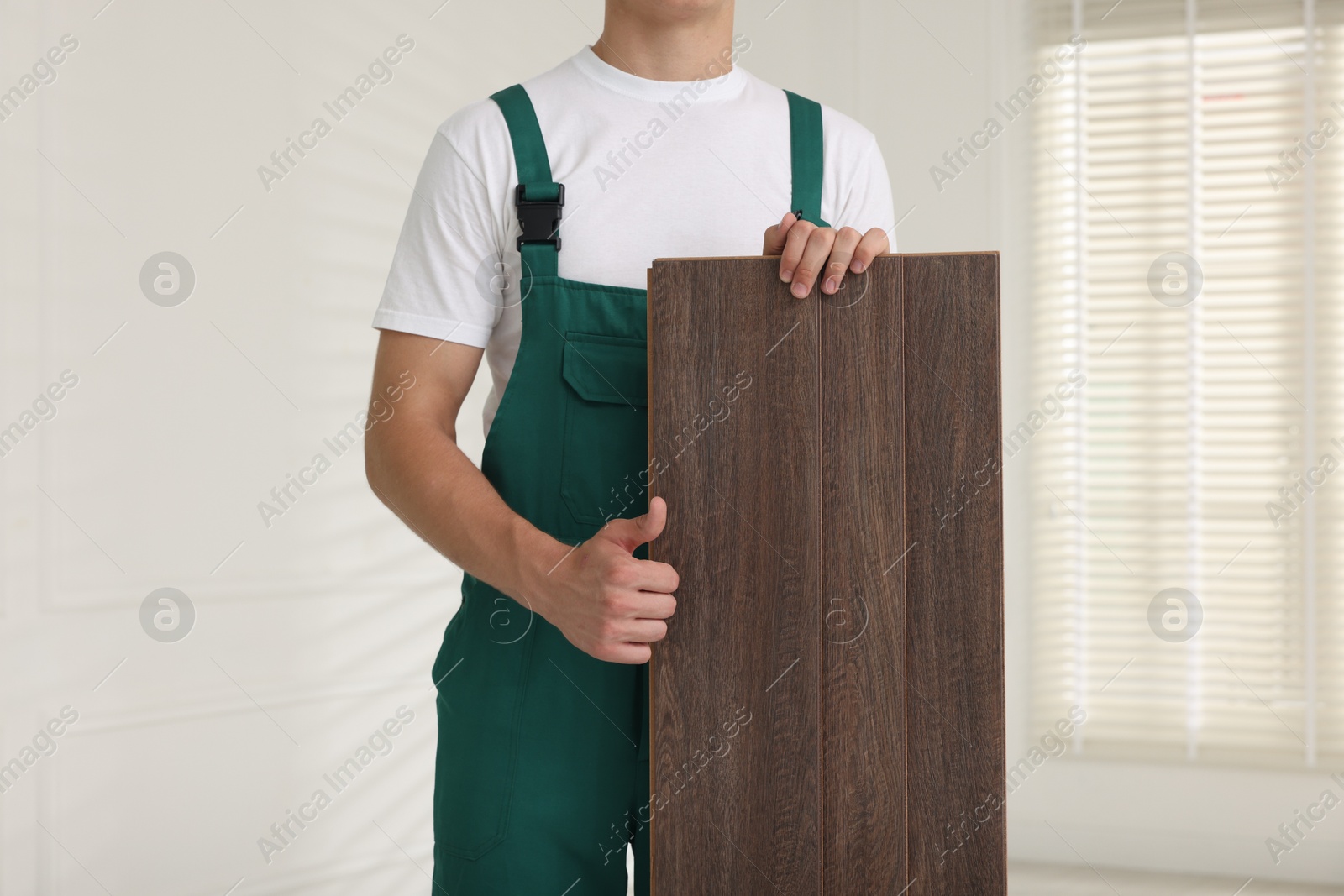 Photo of Worker with samples of wooden flooring showing thumbs up indoors, closeup