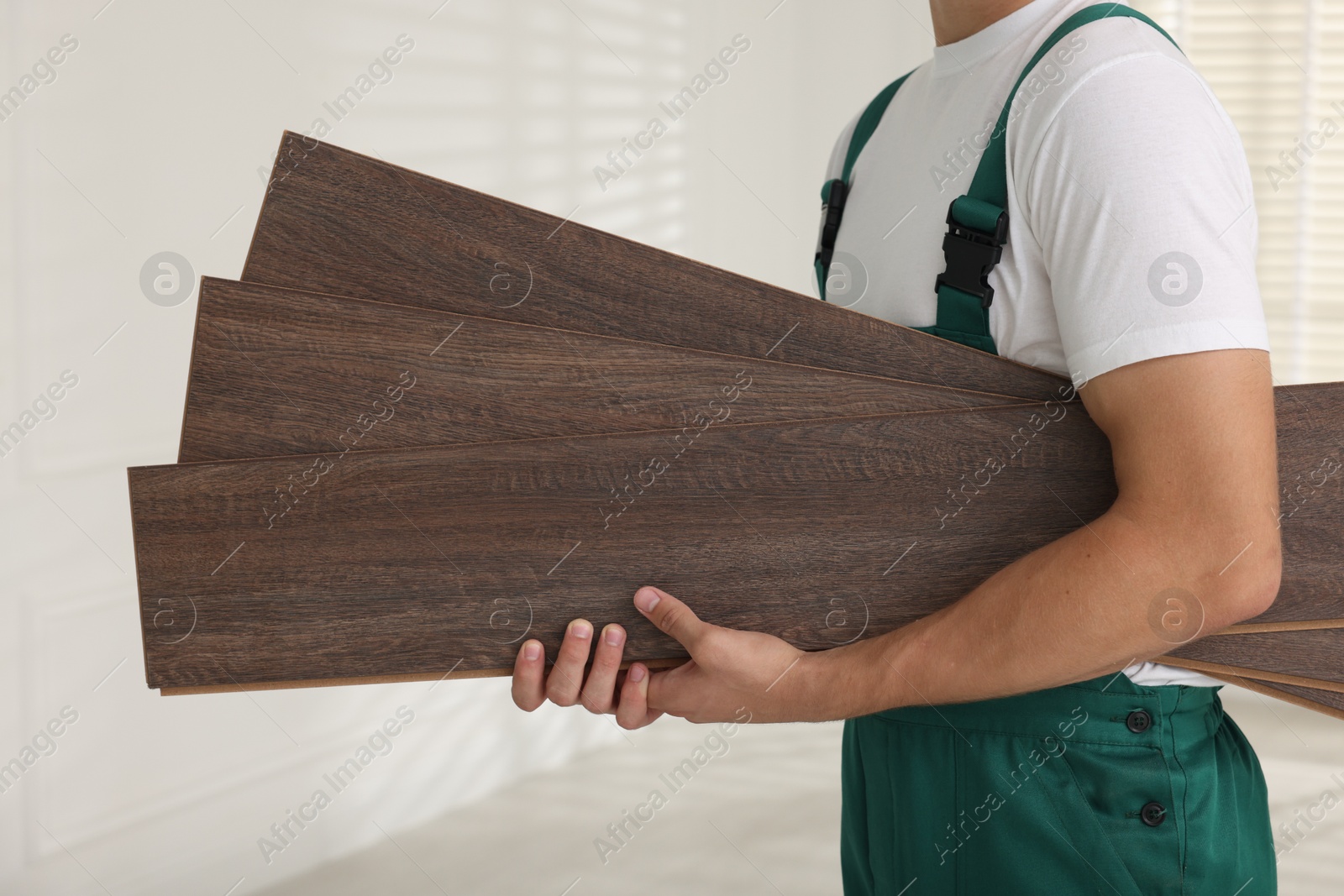 Photo of Worker with samples of wooden flooring indoors, closeup