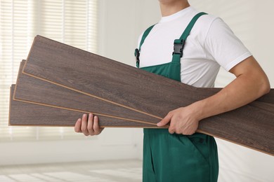 Photo of Worker with samples of wooden flooring indoors, closeup