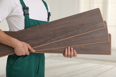 Photo of Worker with samples of wooden flooring indoors, closeup