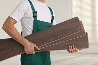 Photo of Worker with samples of wooden flooring indoors, closeup