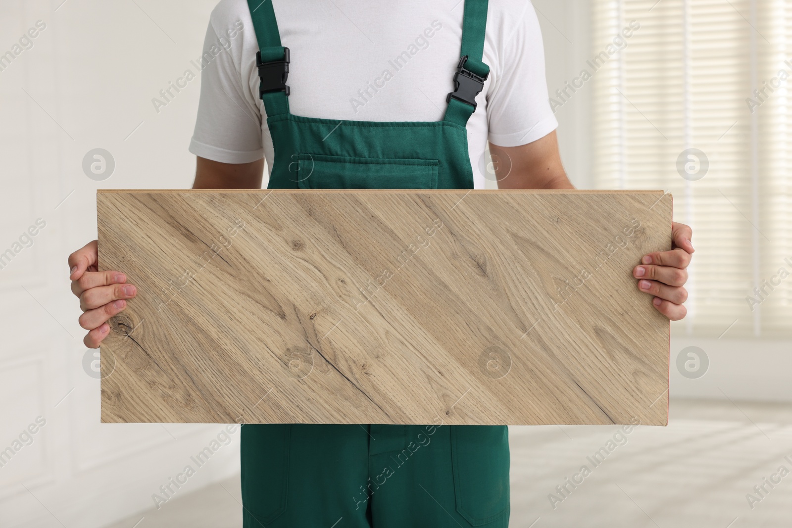 Photo of Worker with sample of wooden flooring indoors, closeup