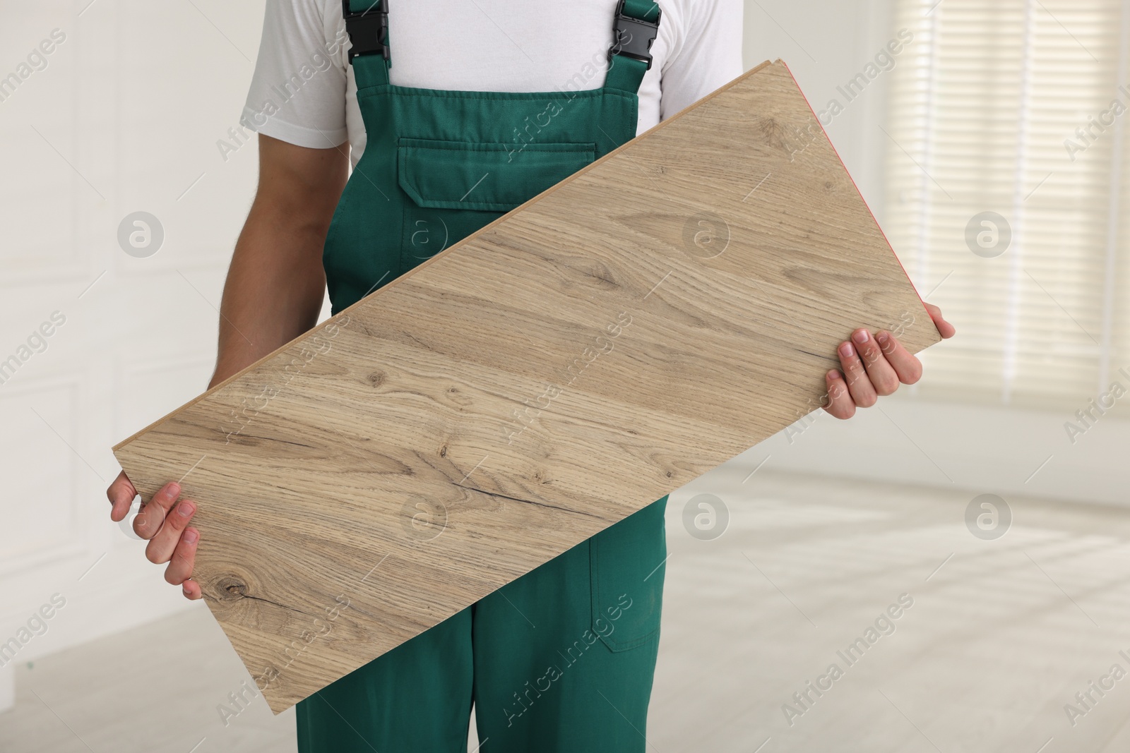 Photo of Worker with sample of wooden flooring indoors, closeup