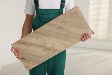 Photo of Worker with sample of wooden flooring indoors, closeup