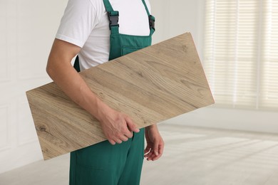 Photo of Worker with sample of wooden flooring indoors, closeup