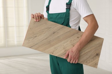 Photo of Worker with sample of wooden flooring indoors, closeup