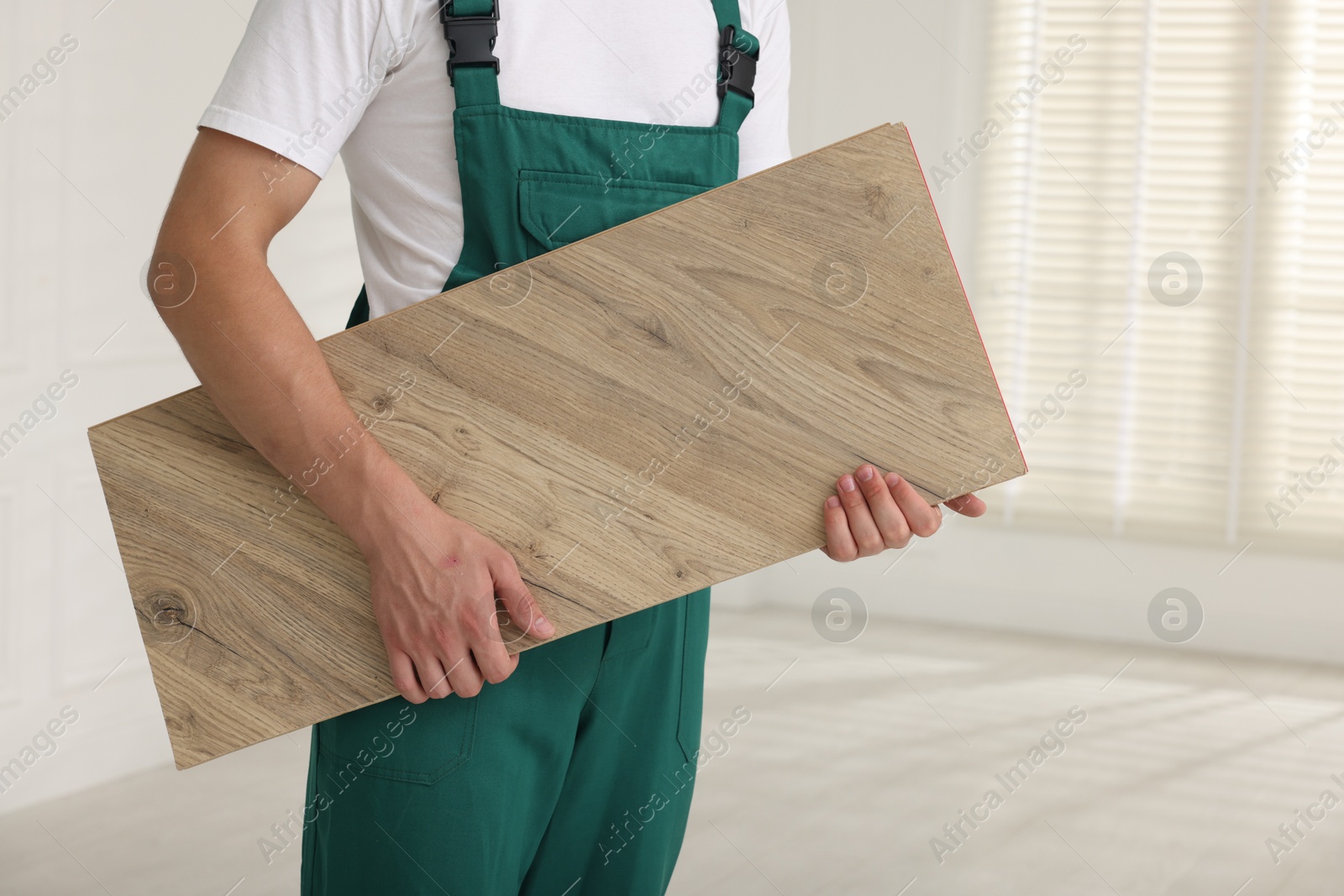 Photo of Worker with sample of wooden flooring indoors, closeup