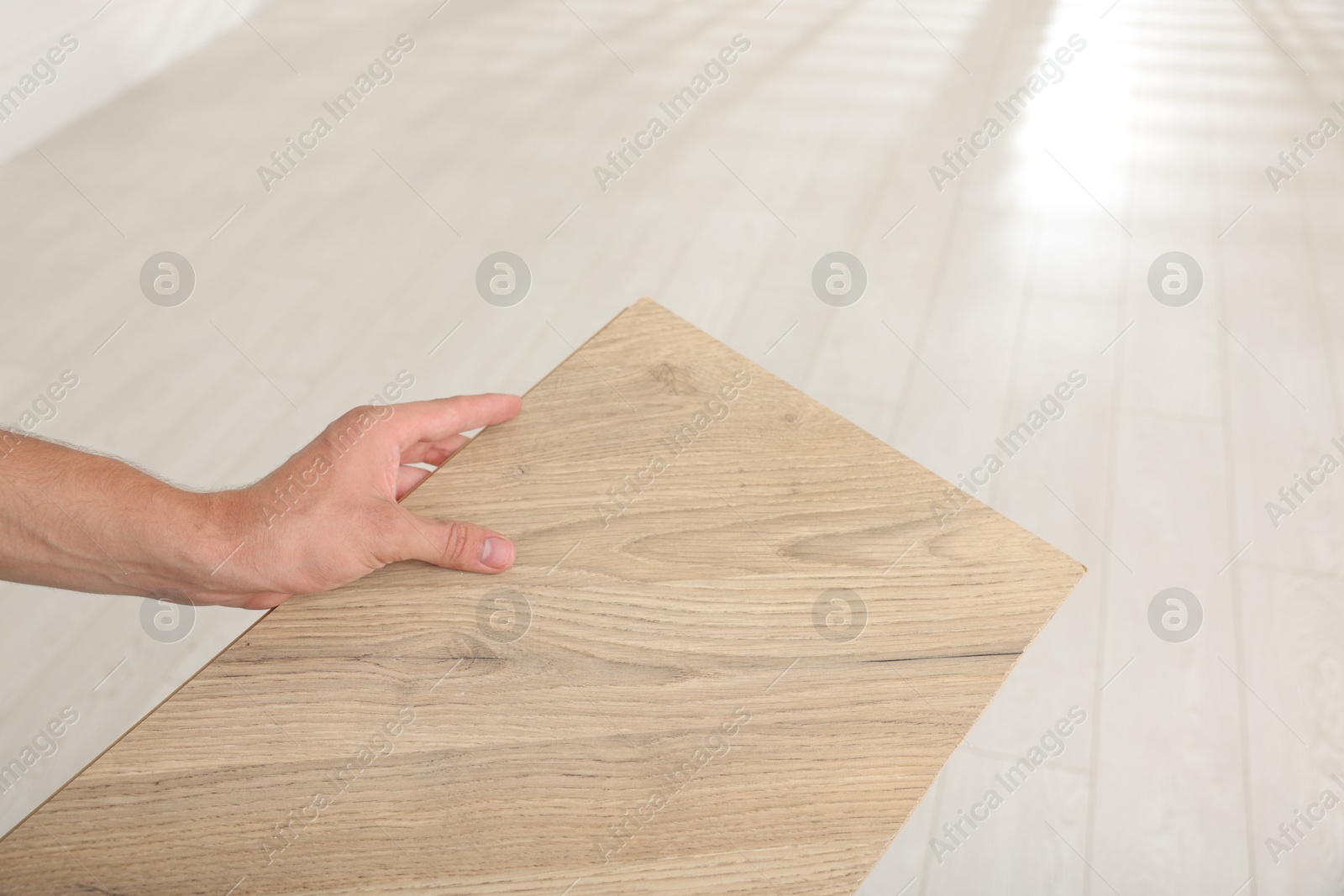 Photo of Man with sample of wooden flooring indoors, closeup