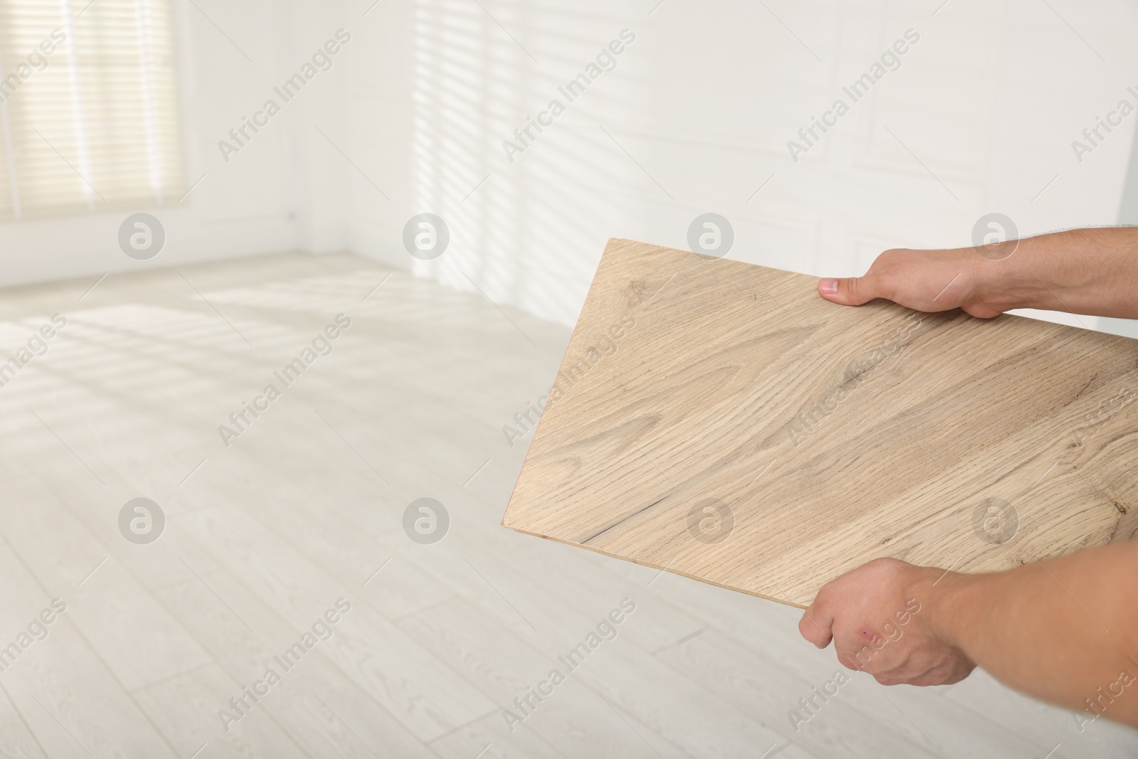 Photo of Man with sample of wooden flooring indoors, closeup. Space for text