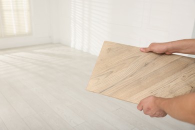 Photo of Man with sample of wooden flooring indoors, closeup. Space for text