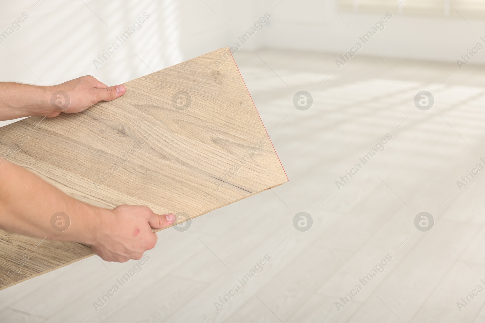 Photo of Man with sample of wooden flooring indoors, closeup. Space for text