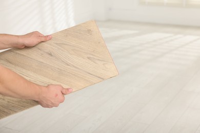 Photo of Man with sample of wooden flooring indoors, closeup. Space for text