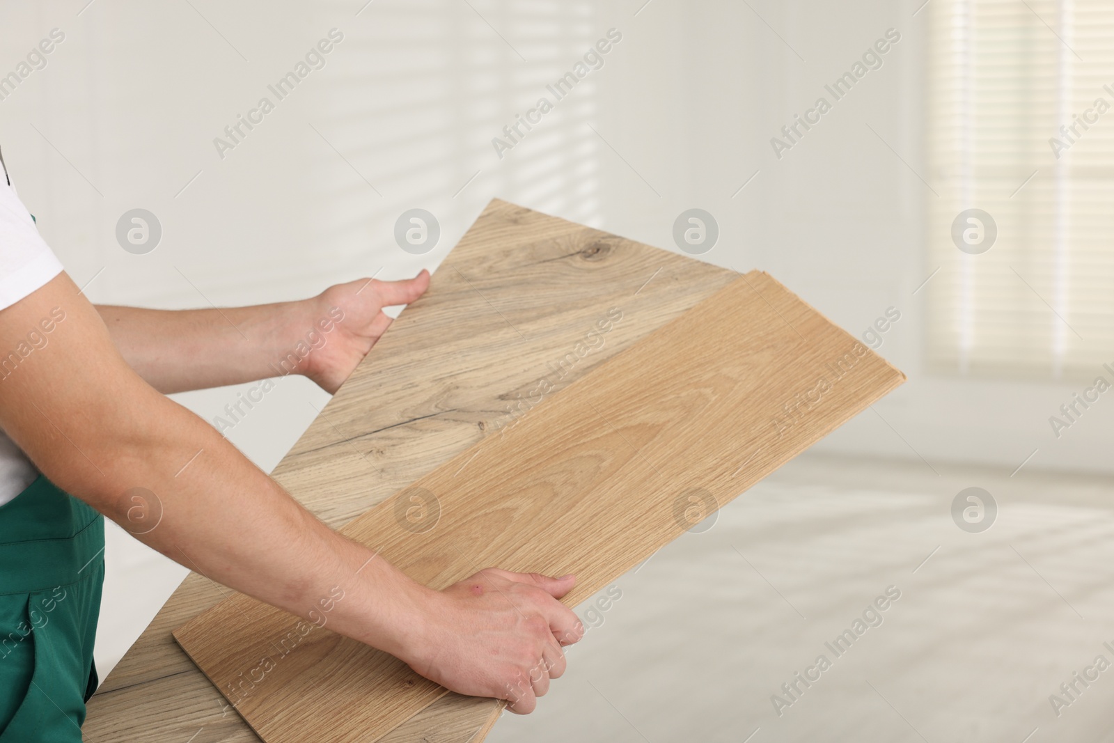 Photo of Worker with samples of wooden flooring indoors, closeup