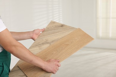 Photo of Worker with samples of wooden flooring indoors, closeup