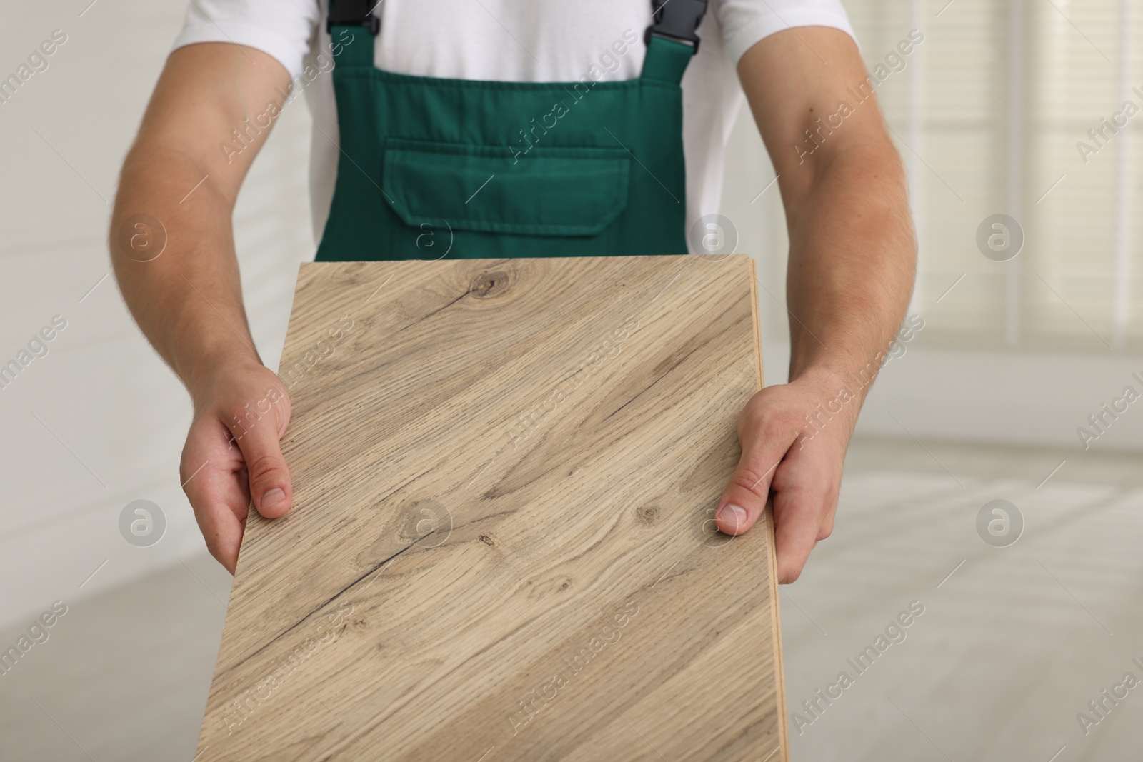 Photo of Man with sample of wooden flooring indoors, closeup