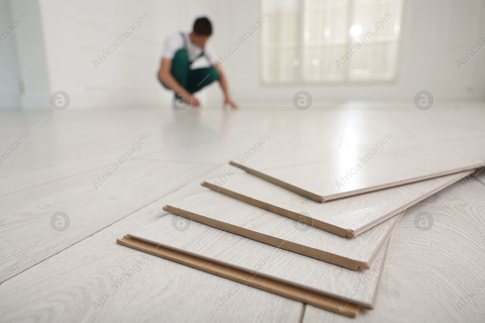 Photo of Worker installing new wooden flooring indoors, selective focus