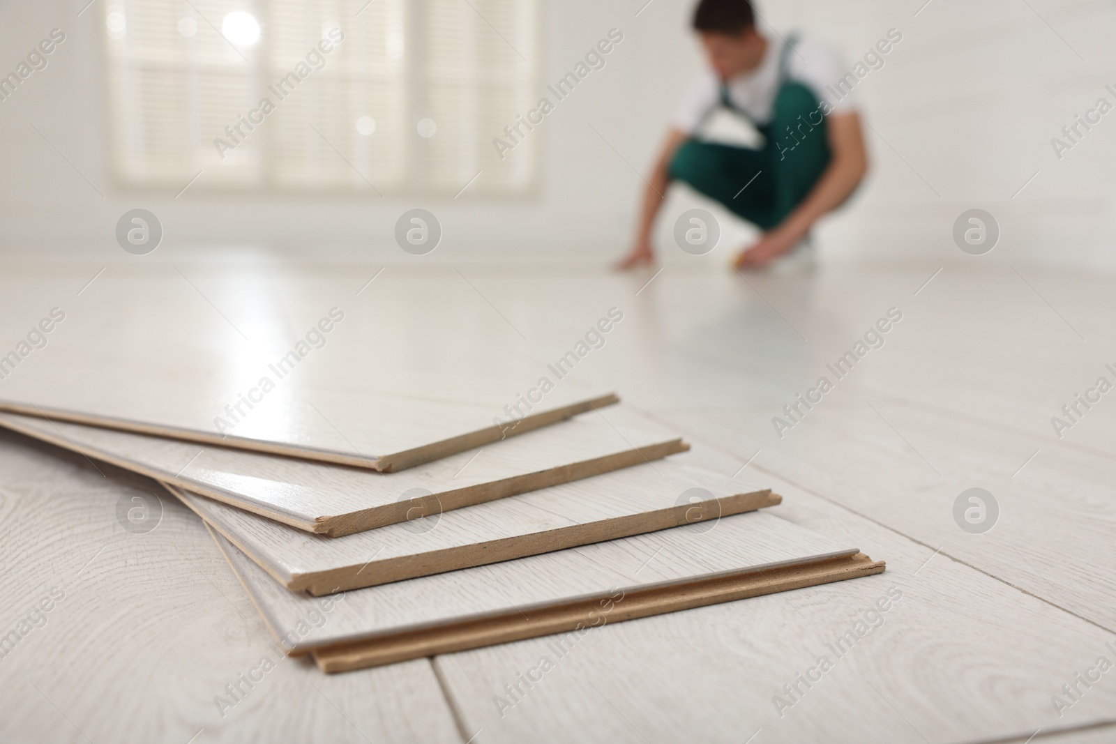 Photo of Worker installing new wooden flooring indoors, selective focus