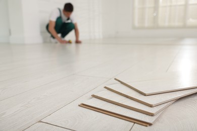 Photo of Worker installing new wooden flooring indoors, selective focus