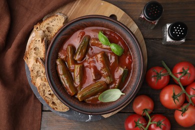 Photo of Tasty stew with okra, tomato sauce, bread and basil on wooden table, flat lay