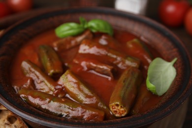 Tasty stew with okra, tomato sauce and basil on table, closeup