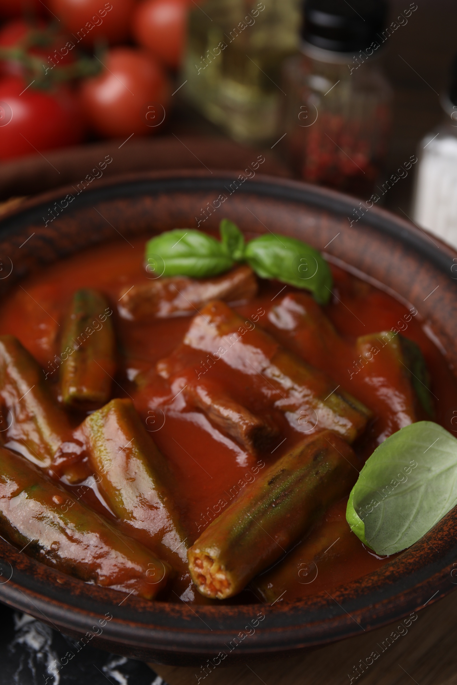 Photo of Tasty stew with okra, tomato sauce and basil on table, closeup