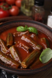 Tasty stew with okra, tomato sauce and basil on table, closeup